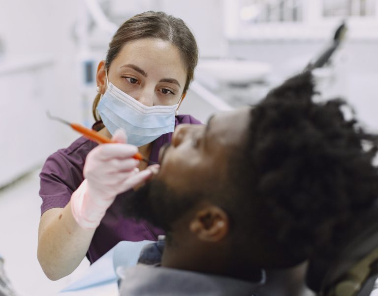 Young african-american man. Guy visiting dentist's office for prevention of the oral cavity. Man and famale doctor while checkup teeth.